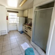 Unrenovated kitchen and shower in same room